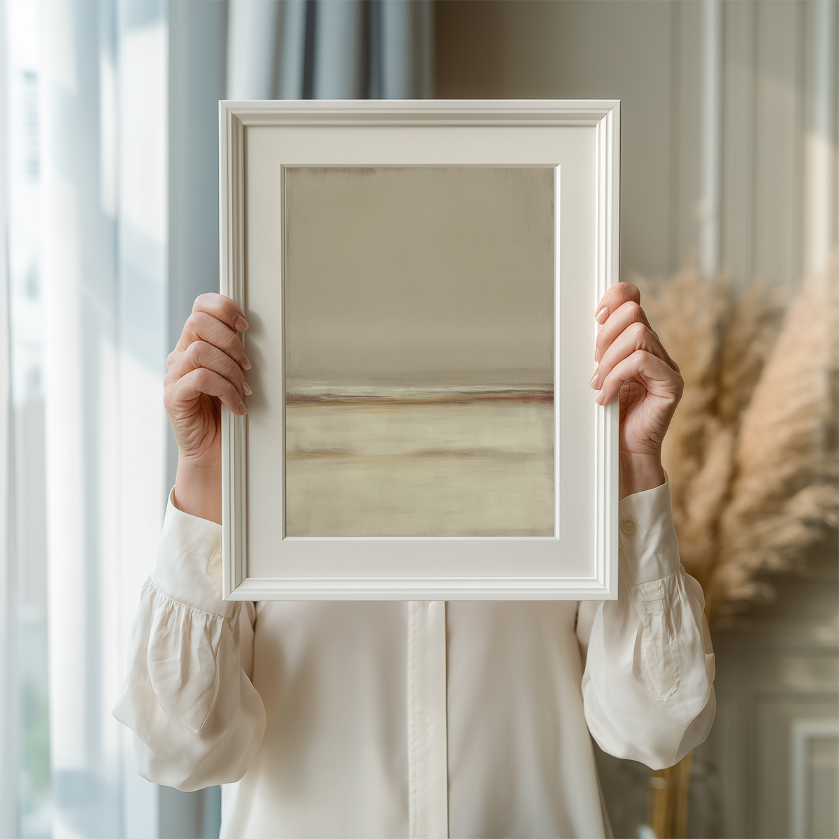 Person holding a framed Neutral Seascape Wall Art | Beige Abstract Canvas featuring soft, minimalist beige and light brown abstract tones perfect for modern living room decor.