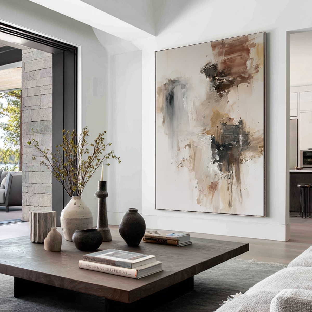 A large vertical abstract canvas print with brown, beige, and black brushstrokes hanging on a white wall in a modern living room setting with a wooden coffee table and decorative vases.