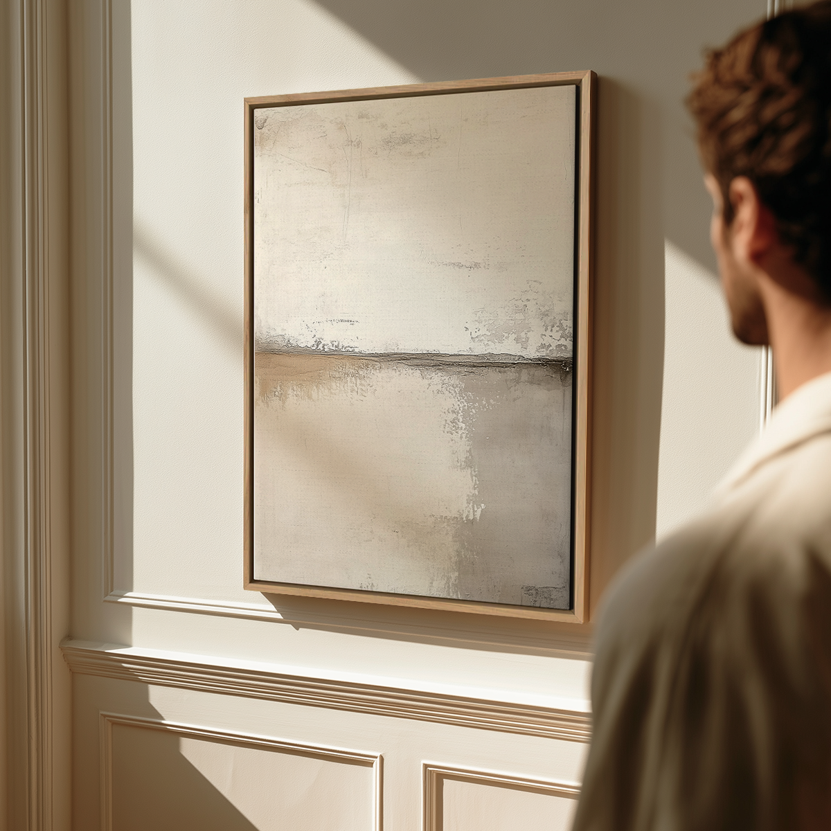 A man viewing a Neutral Abstract Wall Art Print - Scandinavian Modern Beige Canvas Wall Decor with soft beige and gray tones, displayed in a serene, sunlit room with minimalist decor.