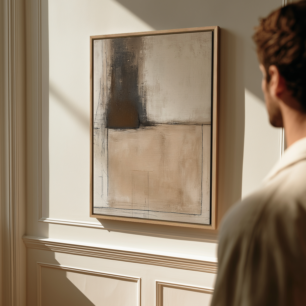 A man looking at an abstract neutral-toned painting featuring layered beige, cream, and dark brown shapes with textured brushstrokes, titled Architectural Abstract Wall Art II | Neutral Minimalist Companion Print | Textured Modern Decor.
