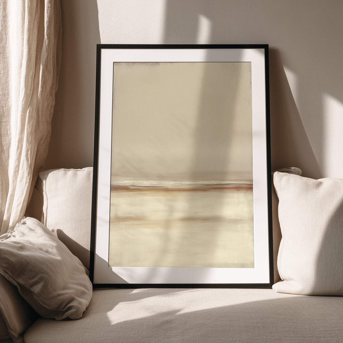 Framed Neutral Seascape Wall Art | Beige Abstract Canvas resting on a beige couch surrounded by soft cushions and natural sunlight casting shadows on the wall.