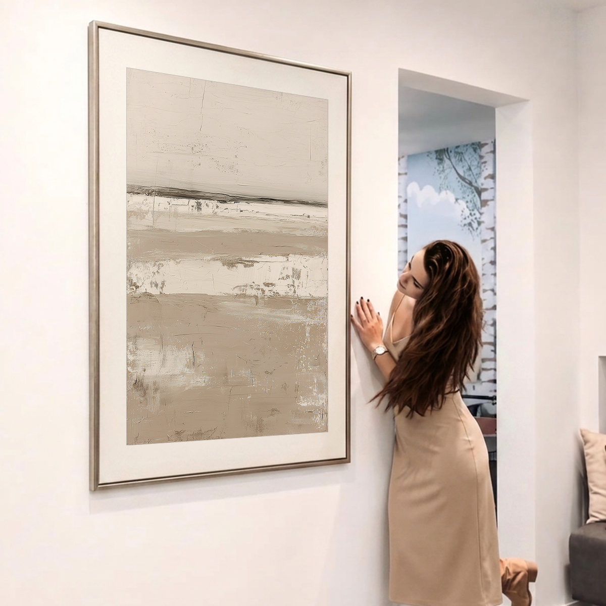 Serene Horizon Wall Art | Neutral Abstract Landscape framed on a white wall as a woman installs it in a modern home interior.